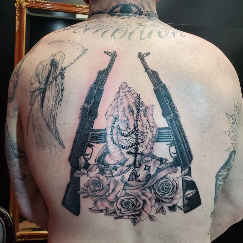 Back collage tattoo, guns, praying hands, Louis Vuitton, roses